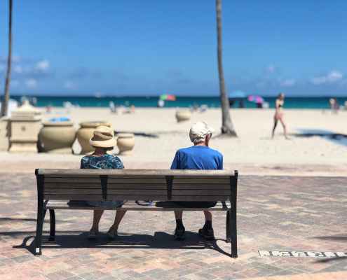 man and woman sitting on brown wooden bench